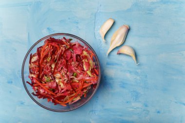 Fırça adında bir kase salata. Pancar, havuç ve lahanayla ince şeritler halinde kesilmiş sarımsak ve ahşap kaplama. Vejetaryen, organik, sağlıklı yiyecekler, diyet, beslenme. Üst görünüm, alanı kopyala.