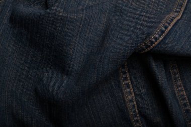 Buruşmuş kot pantolon ya da grunge kot kumaş. Turuncu renkli ve dikişli. Arkaplanı ya da arkaplanı kapat. Tekstil, desenli yüzey. Üniseks kıyafetleri, moda konsepti.