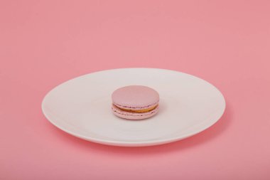 Pembe kağıtta beyaz tabakta pembe bir badem kurabiyesi. Tatlı fırın, kopyalama alanı. Aşırı kilolu, diyet, diyabet, sağlıklı beslenme alışkanlıkları.