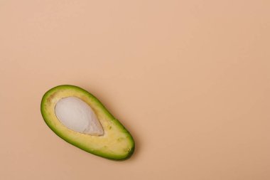 Bej arka planda tohum bulunan yeşil taze avokadonun yarısı. Asgari biçimli bileşim.