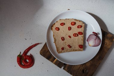 Tavuk etli sandviç. Beyaz tabakta kırmızı biber dilimleri, kırmızı soğanlar, üst manzara. Lezzetli çerez, lezzetli aperatif, hızlı öğle yemeği.