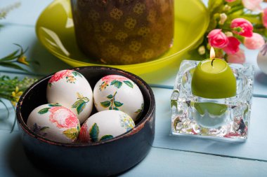 Paskalya süslenmiş yumurta, çiçekler, yanan mum ve Paskalya ekmeği, kulich ya da kremalı kek ve çok renkli şeker parçacıkları. Kapat..