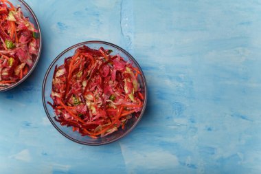 Fırça adında iki kase salata. Pancar, havuç ve lahanalar mavi ahşap arka planda ince şeritler halinde kesilmiş. Vejetaryen, organik, sağlıklı yiyecekler, diyet, beslenme. Üst görünüm, alanı kopyala.