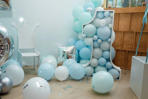 Blue balloons for boy happy birthday party. Number 1 for one year old child. Festive decorative elements, photo zone with chair.