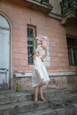 Beyaz elbiseli güzel bir genç kız ve oyuncak bir tavşan tutan güzel bir saç stili.