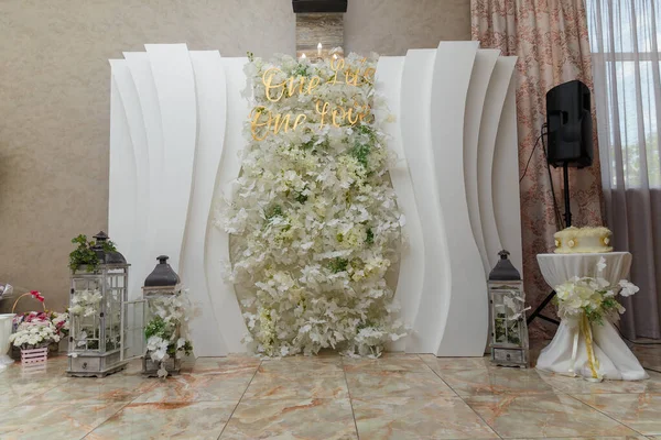 White floral wedding presidium for just married, geometric arch with white flowers and lanterns.