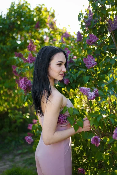 Piękny Ciemnowłosy Model Pozujący Wśród Kwitnących Krzewów Liliowych Wiosennym Tle — Zdjęcie stockowe