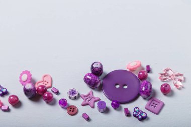 Dikiş ve nakış işlemek için boncuk ve düğme yakın çekim. El işi, bijouterie ve aksesuar yapmak için mor renkli malzemeler. Beyaz arkaplan, alanı kopyala.