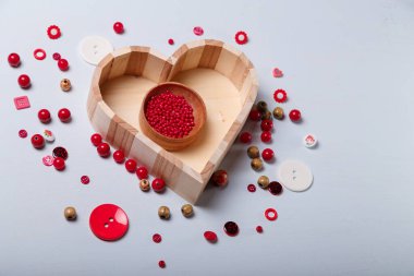 Ahşap kalp şeklinde kırmızı boncuk kutusu ve dikiş ve nakış için düğmeler. El işi, bijouterie ve aksesuar yapmak için malzemeler. Tahta beyaz arkaplan, boşluğu kopyala.