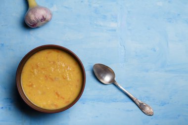 Bir kase bezelye ya da mercimek çorbası püre, mavi ahşap arka planda gümüş kaşıkla taze sarımsak. Sağlıklı organik vejetaryen yemekleri. Üst görünüm, alanı kopyala.