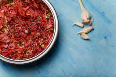 Fırça adında metal bir kase salata. Pancar, havuç ve lahanayla ince şeritler halinde kesilmiş sarımsak ve ahşap kaplama. Vejetaryen, organik, sağlıklı yiyecekler, diyet, beslenme. Üst görünüm, alanı kopyala.