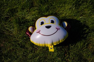 İzmail, Ukrayna. Eylül 2020. Yeşil çimenlikte maymun yüzlü balon. Çocuk partisi konsepti.