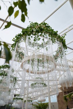 Dekoratif yeşil sarmaşık bitkisi olan güzel beyaz avize açık hava restoranının iç tarafında.