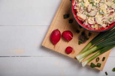 Turp, yeşil soğan, maydanoz, beyaz ahşap arka planda kırmızı kasede yumurta salatası. Sağlıklı yeme alışkanlıkları, organik yiyecekler, diyet ve beslenme konsepti. Üst görünüm, alanı kopyala.