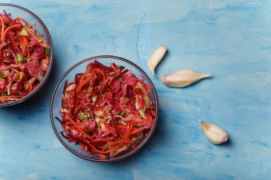 Fırça adında iki kase salata. Pancar, havuç ve lahanayla ince şeritler halinde kesilmiş sarımsak ve ahşap kaplama. Vejetaryen, organik, sağlıklı yiyecekler, diyet, beslenme. Üst görünüm, alanı kopyala.