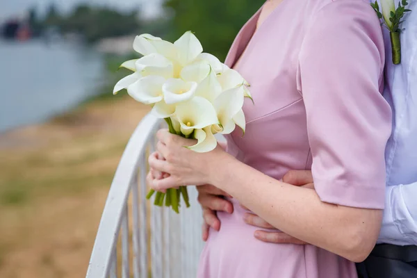 Bräutigam Umarmt Braut Rosa Kleid Hält Weißen Calla Lilien Strauß — Stockfoto