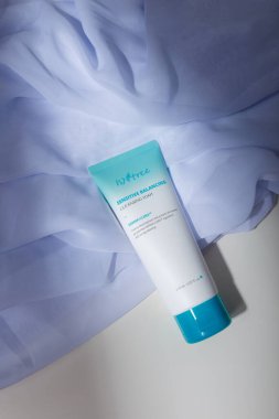 İzmail, Ukrayna, Temmuz 2021. Beyaz kumaş üzerine mavi başlıklı beyaz tüp, doğal katı gölgeler. Yüz bakımı kozmetikleri, krem