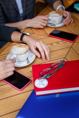 İzmail, Ukrayna. Mayıs 2021. İş arkadaşları iş yemeği ya da kahve molası veriyor. Tabletli, akıllı telefonlu, defterli kadın elleri..