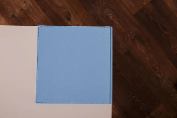 Spine of book, photobook, notebook or photoalbum in light blue leather cover on white table background. Top view, copy space.