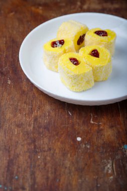 Türk lokumu, jöleli sarı lokum rulosu ve beyaz tabakta hindistan cevizi gevreği, ahşap arka plan. Doğu tatlıları, doğu yemekleri. Geleneksel lezzetli tatlı. Uzayı kopyala Üst görünüm
