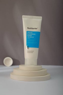İzmail, Ukrayna. 9 Temmuz 2024. Gerçek Bariyer Kremi Temizleyici Köpük. Beton merdivenlerdeki Kore kozmetik tüpü gri arka planda duruyor. Ürün sunumu, reklam afişi