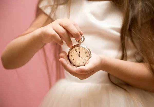 round clock in the hands of a child. arrows at midnight