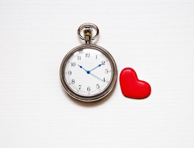 Beyaz arka planda yuvarlak saat ve kırmızı kalp. Süre