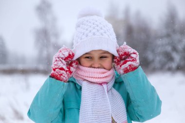 Küçük kız, doğada kışın şapkasını kafasına geçirir..