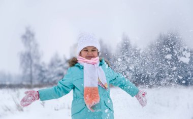 Kışın doğadaki bebek karla oynuyor.