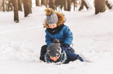 İki çocuk güzel bir kış ormanında karda oynuyor..