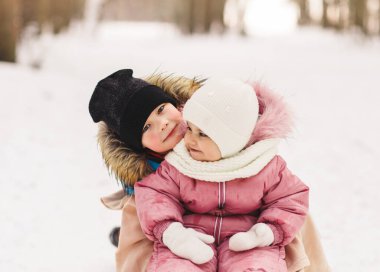 Küçük erkek ve kız kardeş parkta kış yürüyüşüne çıktılar.