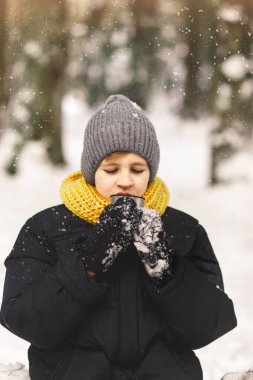 Genç bir çocuk kış ormanında sıcak çay içer. Renkler 2021