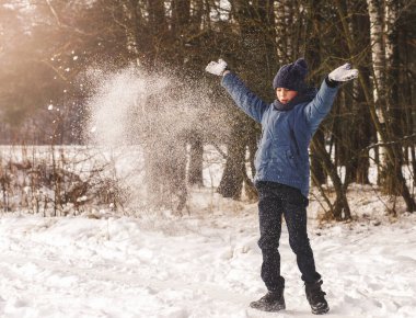 Oğlan güneşli bir günde kışın karla oynar