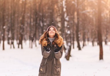 Güzel kız güneşli bir günde kış parkında karın tadını çıkarır.
