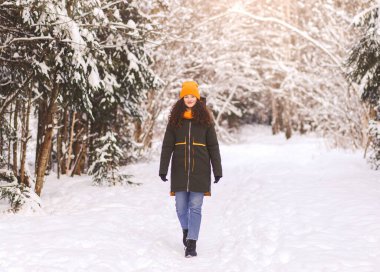 Güzel kız kışın parkta karda yürür.
