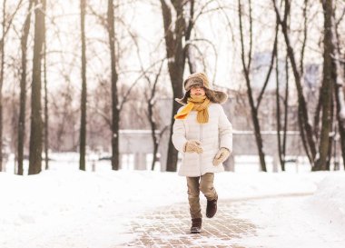 Oğlan kışın parkta koşar.
