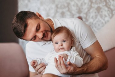 Genç, güzel bir baba ve parlak bir odada kucağında küçük bir kız.