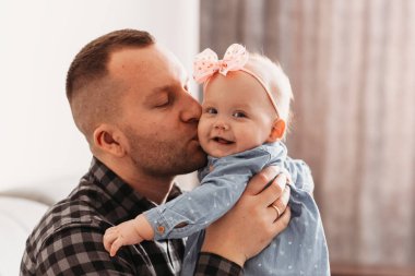 Yakışıklı bir genç adam babası küçük kızını öpüyor. Babasının kollarında bir kız.