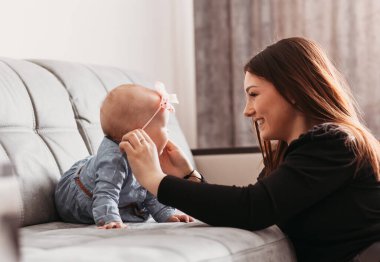 Genç bir anne kızıyla kanepede oynuyor. Mutlu Annelik