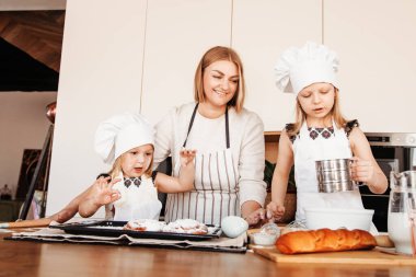 Mutfakta bir arada duran mutlu anne ve iki kız fırın yapmayı öğrenmeye hazırlar. Aile ilişkileri için fikir.
