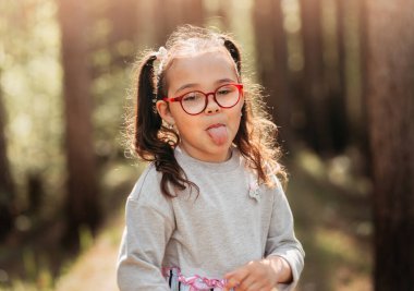 Gözlüklü tatlı kız suratını ekşitiyor ve yazın dilini gösteriyor.