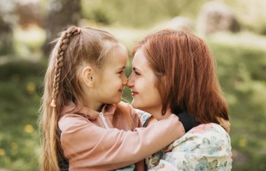 Anne ve kızı birbirlerine bakıyorlar. Bir kadın ve bir çocuğun yakın plan portresi.
