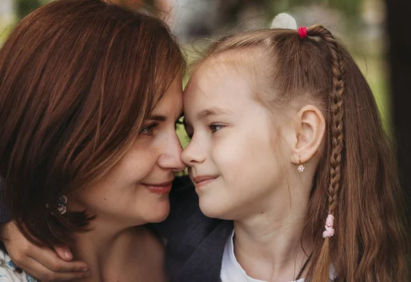 Anne ve kızı birbirlerine bakıyorlar. Bir kadın ve bir çocuğun yakın plan portresi.