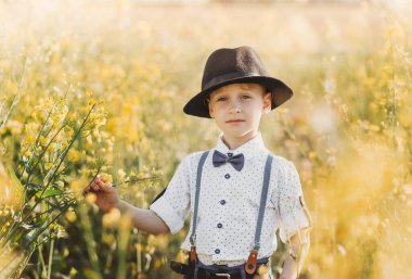 A little boy in a hat in an oilseed rape field. Rural landscape