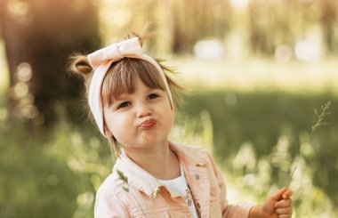 Küçük tatlı kız yazın parkta oynuyor ve eğleniyor.