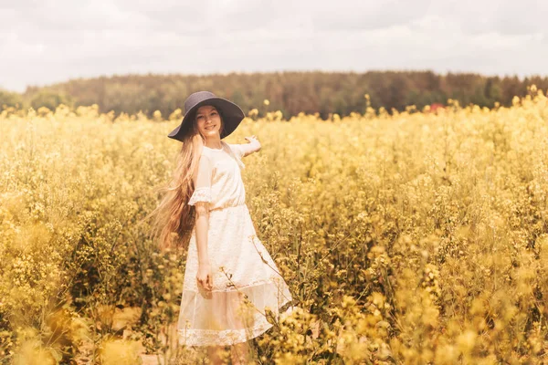 若い幸せな女の子は 菜の花の分野で自然を楽しんでいます 若者と自由の概念 — ストック写真