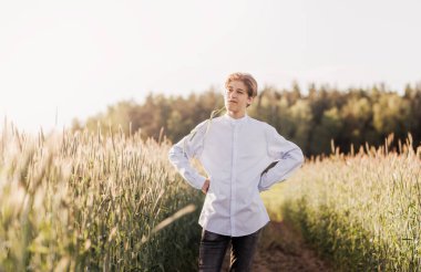 Genç yakışıklı adam buğday tarlasında yürüyor.