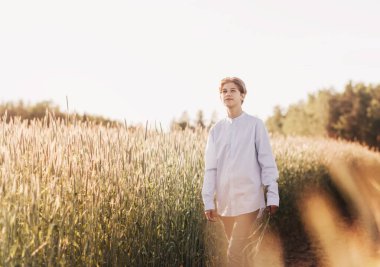 Genç yakışıklı adam buğday tarlasında yürüyor.