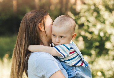 Genç bir anne kollarına alır ve yazın doğada küçük bir çocuğa sarılır.