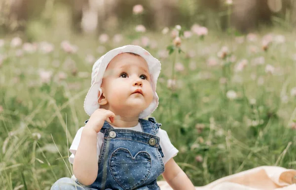 Een Klein Meisje Een Witte Pet Zit Het Park Tussen — Stockfoto